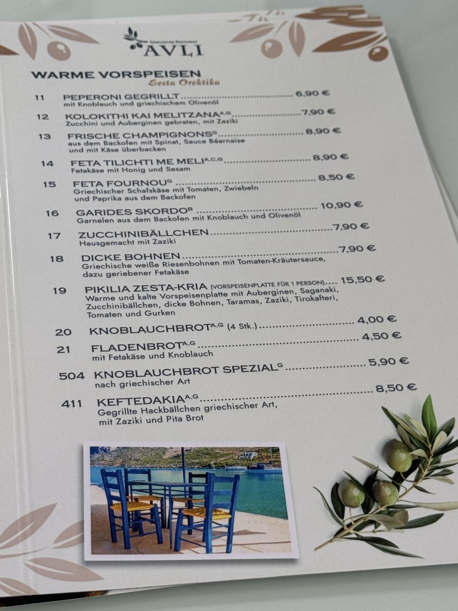 Aufgeschlagene Speisekarte des Restaurants Avli mit warmen Vorspeisen, Preisen und Foto auf gestaltetem Innenblatt