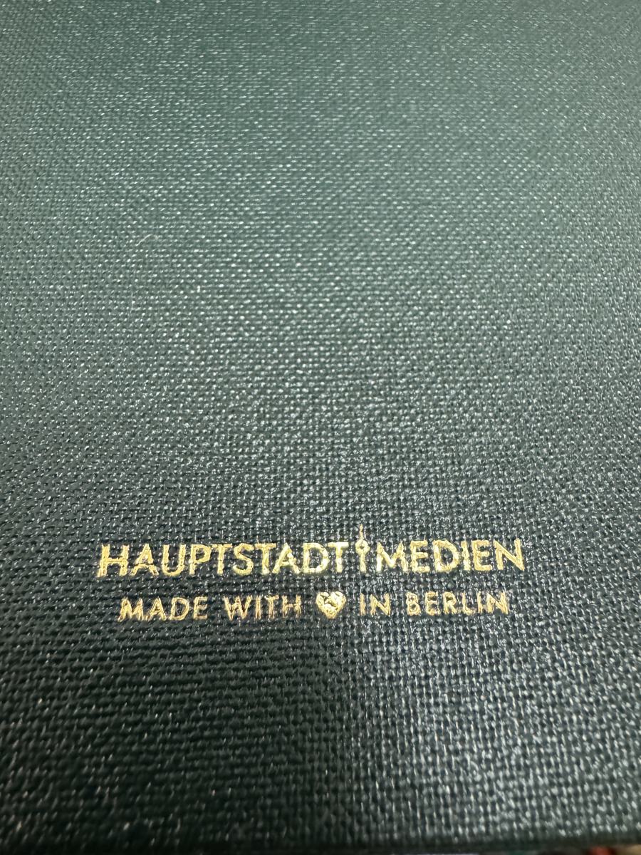 Goldprägung „Hauptstadt Medien – Made with Herz in Berlin“ auf der Rückseite einer dunkelgrünen Speisekartenmappe