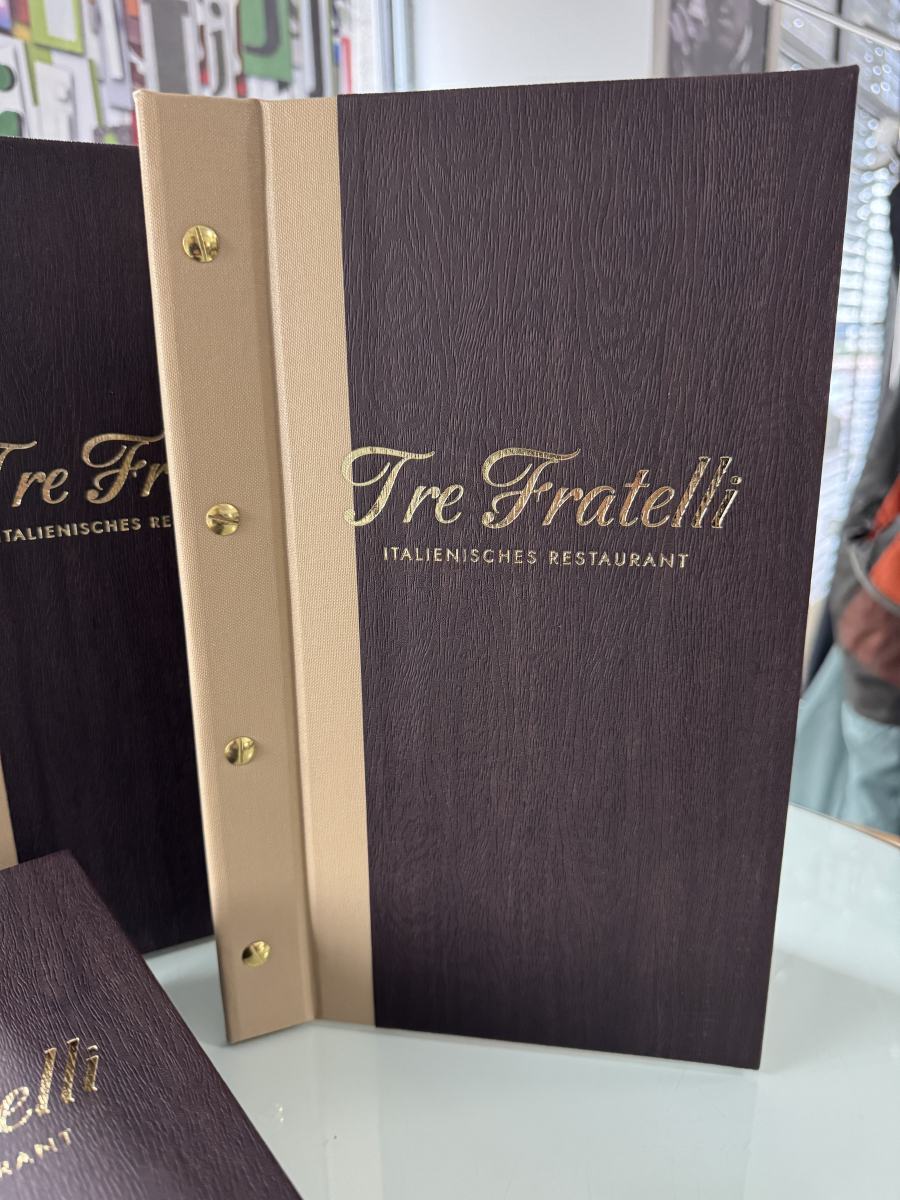 Zweifarbige Speisekartenmappen im Querformat für das Ristorante Tre Fratelli in Beige und Holzoptik mit Goldschrauben