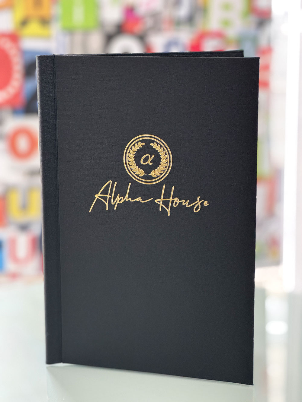 Schwarze Klemmspeisekarte mit filigraner Goldprägung für das Alpha House