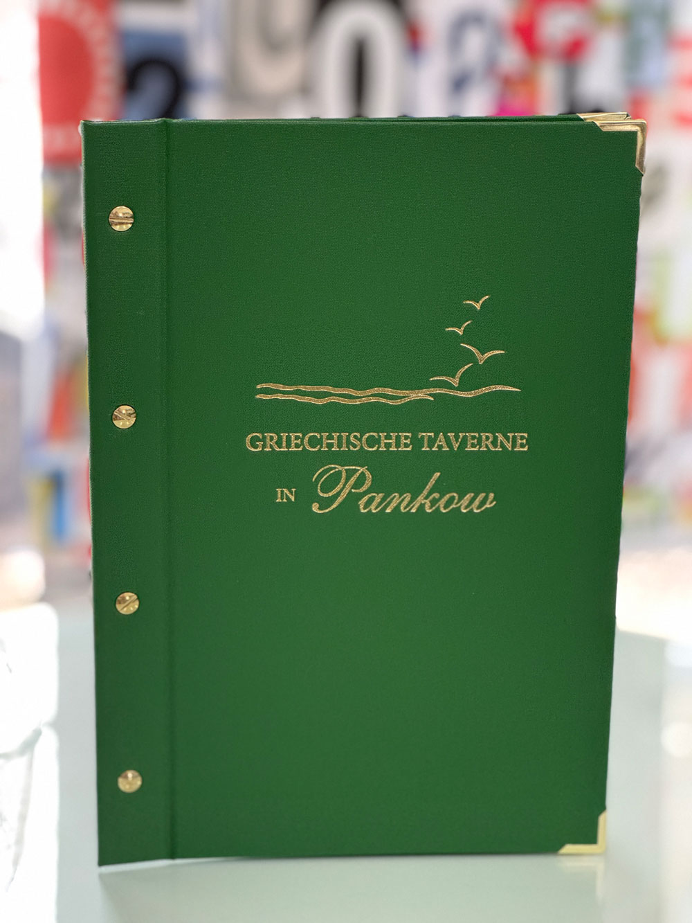 Grüne Speisekartenmappe mit Goldprägung und Metallecken für die Griechische Taverne in Pankow