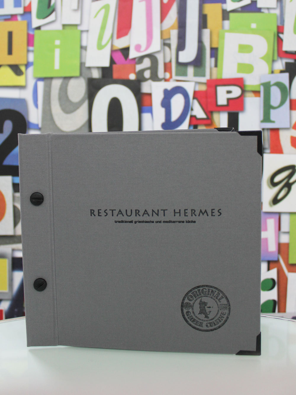 Graue Speisekartenmappe im Querformat mit schwarzer Prägung und schwarzen Schrauben für das Restaurant Hermes